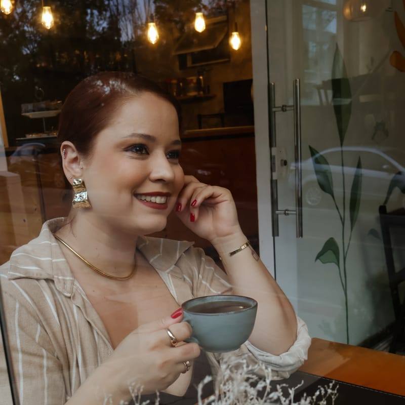 Dayana Regonini Baldan sorrindo em um café, segurando uma xícara
